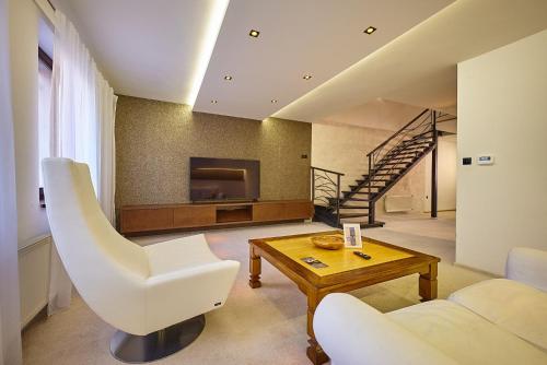 a living room with a white chair and a table at HOTEL Garni PATRIOT in Trnava