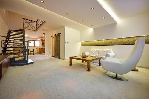 a living room with a white chair and a table at HOTEL Garni PATRIOT in Trnava