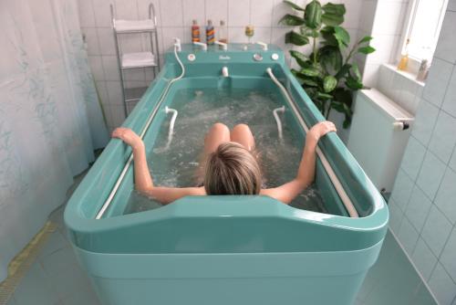 Eine Frau sitzt in einem Pool voller Wasser in einer Badewanne in der Unterkunft Pension Josef in Franzensbad
