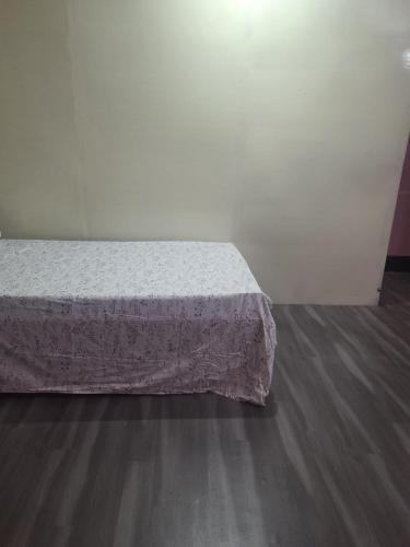 a bed in a white room with a wooden floor at AKSHITA Guest House in Guwahati