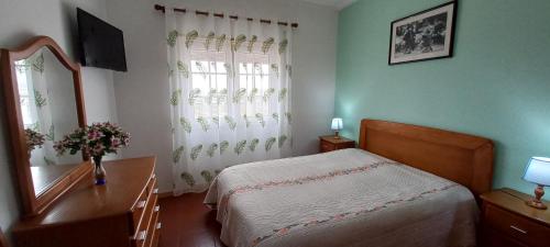 a bedroom with a bed and a table and a window at Casa Olhos de Mar - 7 min pé Praia in Peniche
