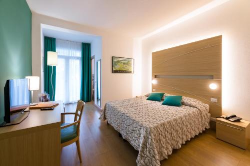 a hotel room with a bed and a desk and a computer at Hotel Mioni Royal San in Montegrotto Terme