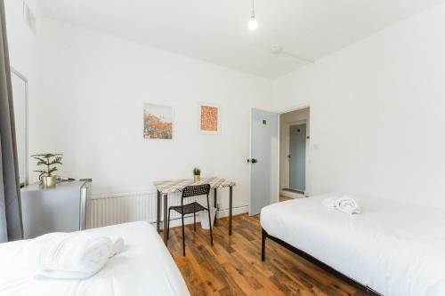 - une chambre avec 2 lits et une table avec une chaise dans l'établissement Upton Park Bedrooms 25 min to Central London, à Londres