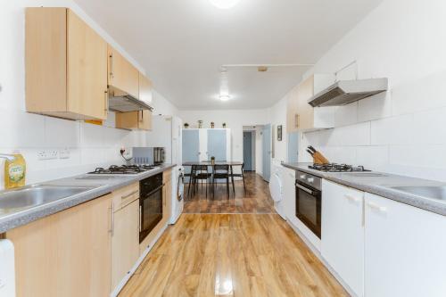 a kitchen with white appliances and a wooden floor at Upton Park Bedrooms 25 min to Central London in London