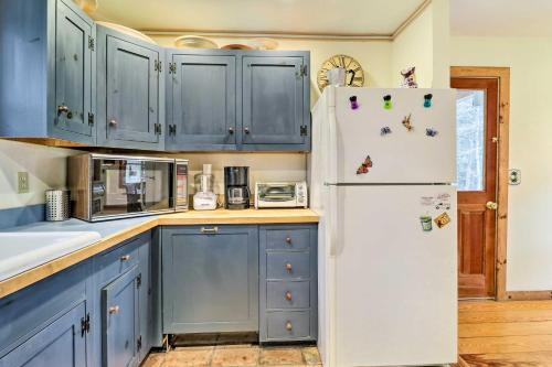 a kitchen with blue cabinets and a white refrigerator at Cozy Monterey Home with Porch Walk to Lake Garfield in Monterey