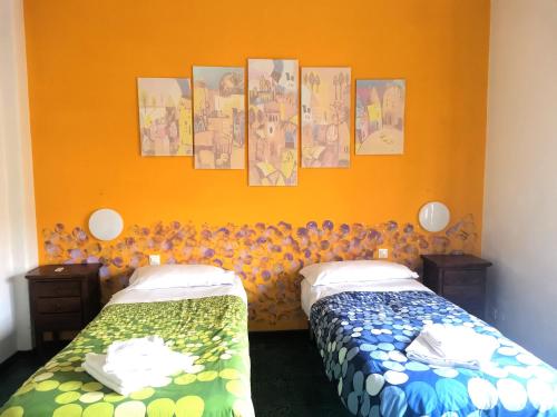 2 Betten in einem Zimmer mit orangefarbener Wand in der Unterkunft My Vatican House in Rom
