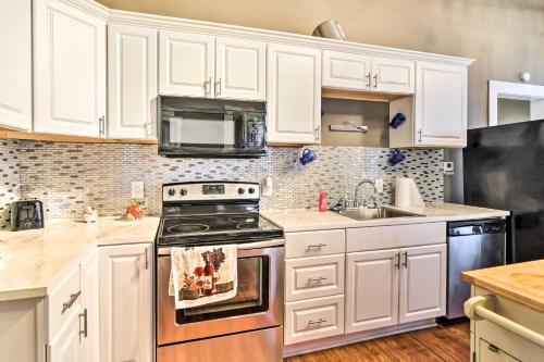 a kitchen with white cabinets and a stove and a sink at Stylish Vicksburg Apt with Porch - 2 Mi to Casino! in Vicksburg