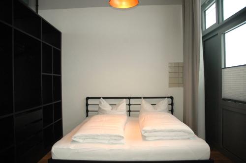 um quarto com uma cama com lençóis brancos e almofadas em Apartmenthaus Ahorn em Mittelberg