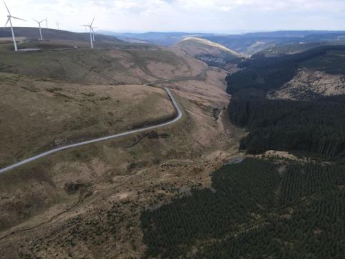 a road in the middle of a mountain with wind turbines at Mountain Escape - Cosy 2 bed house in Afan Valley in Port Talbot