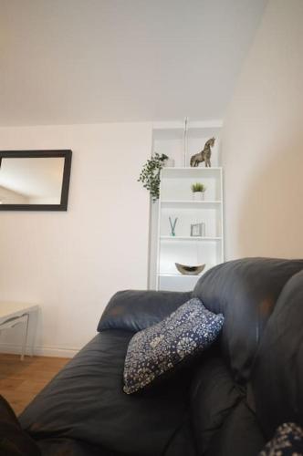 a black leather couch in a living room with a cat on a shelf at Mountain Escape - Cosy 2 bed house in Afan Valley in Port Talbot