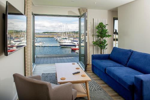 a living room with a blue couch and a view of a harbor at The Salt Lodge in Troon