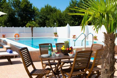 a table and chairs in front of a swimming pool at Villa Paradiso: Near beach, superb pool and garden in Astrakeri