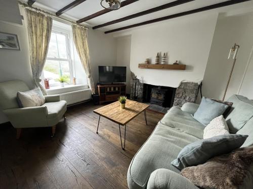 a living room with a couch and a table at Attenborough Cottage - 2 Bedroom Cottage in Tredegar