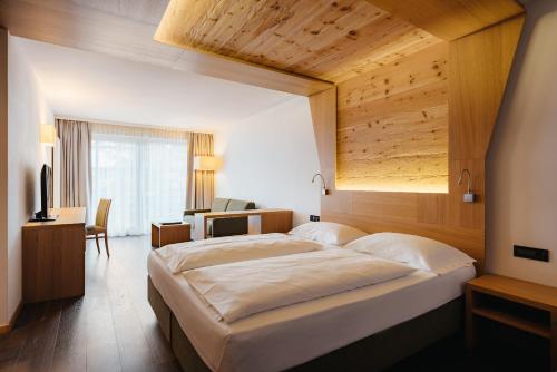 sypialnia z dużym łóżkiem i drewnianym sufitem w obiekcie Hotel Melodia del Bosco w mieście Badia