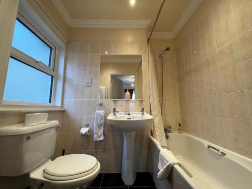 a bathroom with a toilet and a sink and a tub at Atlanta Guest House in Eastbourne