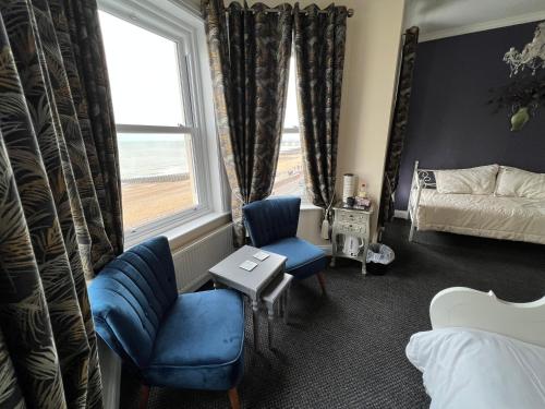 a bedroom with blue chairs and a bed and a window at Atlanta Guest House in Eastbourne