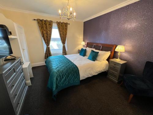 a bedroom with a bed with a blue blanket and a television at Atlanta Guest House in Eastbourne