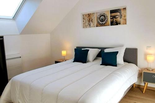 a bedroom with a large white bed with blue pillows at La Petite Loge à Azay-le-Rideau in Azay-le-Rideau