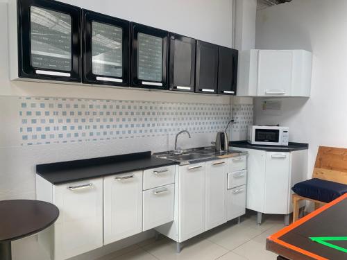 a kitchen with white cabinets and a microwave at The Mural Hostel Bogotá in Bogotá