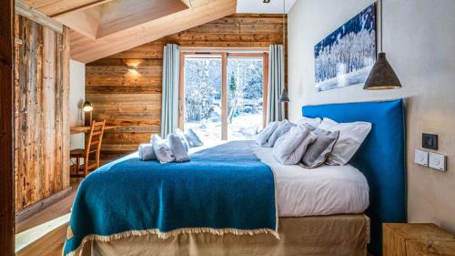 une chambre avec un lit bleu avec une fenêtre dans l'établissement Chalet du Bois, à Chamonix-Mont-Blanc