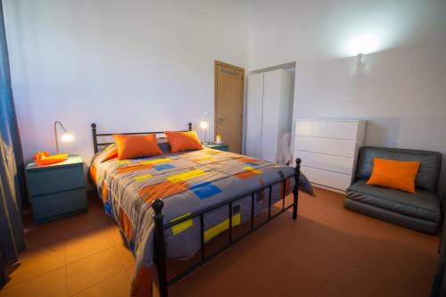 Un dormitorio con una cama con almohadas naranjas y una silla. en Monte Da Baía Do Tonel, en Zambujeira do Mar