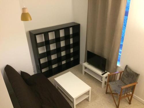 ein Wohnzimmer mit einem Sofa und einem TV in der Unterkunft Maison au calme proche des transports in Lille