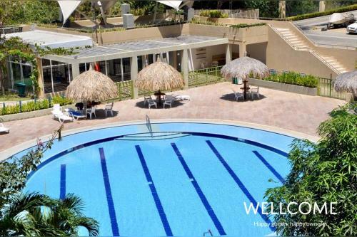 una piscina con sombrillas y un complejo en NUEVO! Hermoso y Exclusivo Apto para 4 en Zazué, en Santa Marta