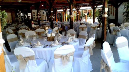 a room full of tables and chairs with white tablecloths at Tassi Halászcsárda - Sügér ház in Tass