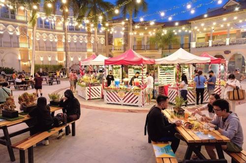 un groupe de personnes assises à des tables devant un bâtiment dans l'établissement Venice Luxury Residences, à Manille