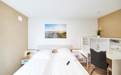 ein weißes Schlafzimmer mit einem Bett und einem Schreibtisch in der Unterkunft Nordseestern in Cuxhaven