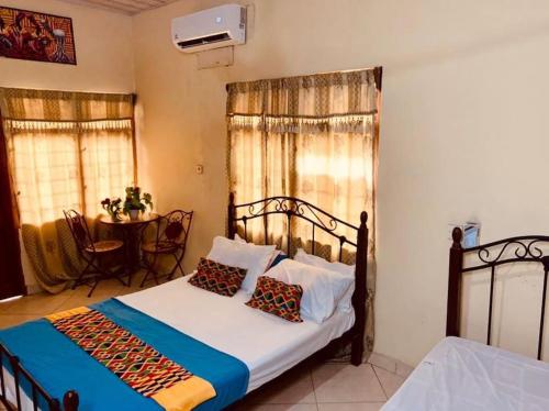 a bedroom with a bed and a table and windows at Kangaroo Pouch Beach Resort in Busua