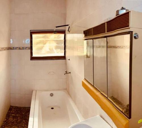 ein Bad mit einer Badewanne, einem WC und einem Fenster in der Unterkunft Kangaroo Pouch Beach Resort in Busua