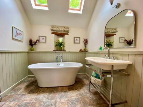 y baño con 2 lavabos, bañera y espejo. en Stunning barn minutes from the Lake District, en Penrith