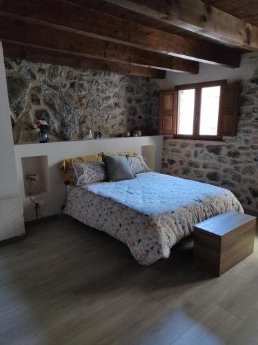 1 dormitorio con cama y pared de piedra en Casa Puri en Jérica
