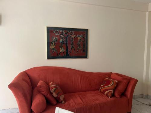 a red couch in a living room with a painting at NMG Comforts in Roseau