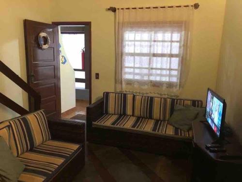 uma sala de estar com um sofá e uma televisão em Duplex 450m da Praia do Peró com Enxoval, Wi-Fi, TV a Cabo, Estacionamento em Cabo Frio