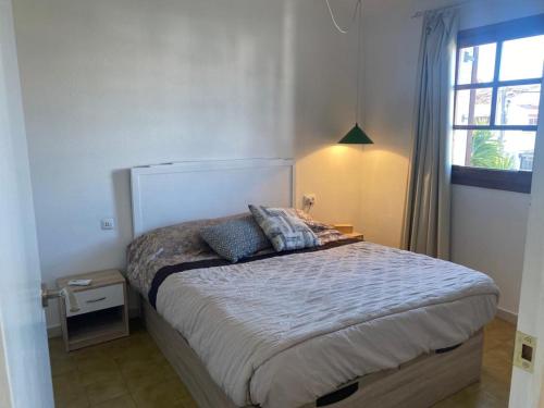 Schlafzimmer mit einem Bett und einem Fenster in der Unterkunft Adosado cerca de la playa in Torredembarra