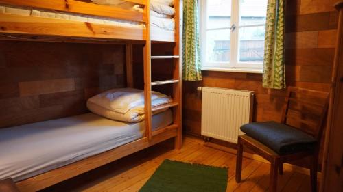 a room with bunk beds and a chair and a window at Hütte mit Herz im Harz in Meisdorf