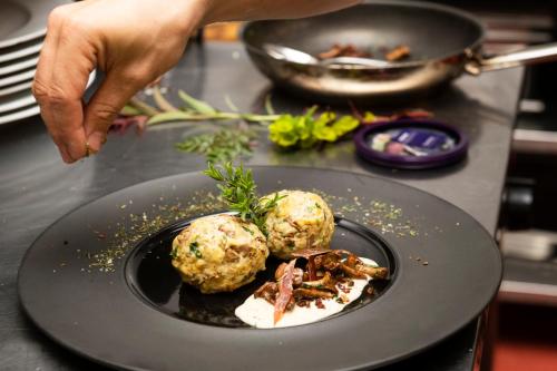 a person reaching for a plate of food on a table at Sepp & Hannis Suiten im Dorf in Neustift im Stubaital