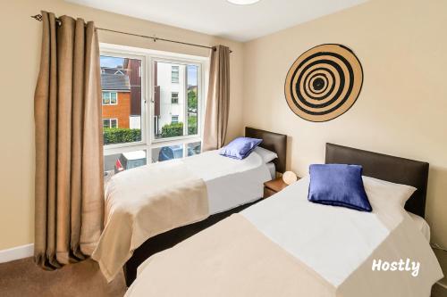 two beds in a room with a window at Puffin Way - Comfortable, spacious house with parking in Reading