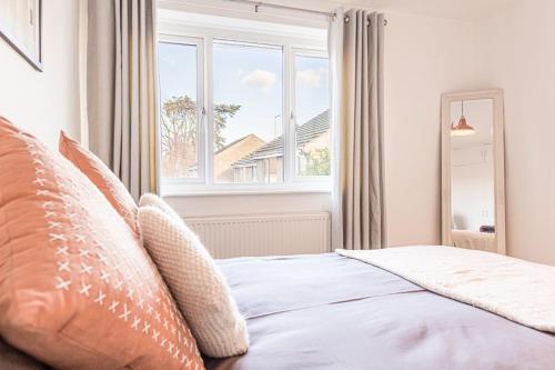 1 dormitorio con cama con almohadas y ventana en Modern 2 BD w/ Garden in the Heart of Tetbury!, en Tetbury