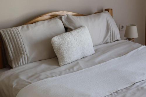 a bed with white sheets and a pillow on it at City Center - TERRA Apartment in Pristina