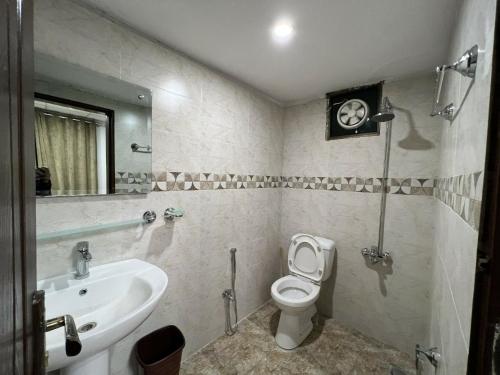 a bathroom with a white toilet and a sink at The Realtors Inn Luxurious Cottage Murree in Murree