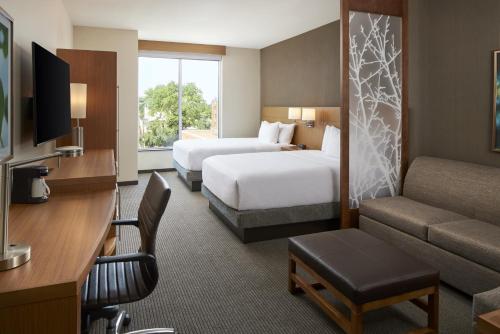 a hotel room with two beds and a couch at Hyatt Place Evansville in Evansville