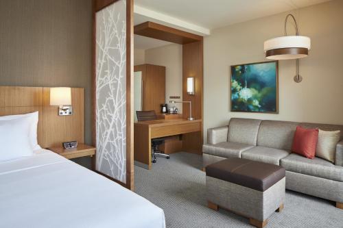 a hotel room with a bed and a couch and a desk at Hyatt Place Evansville in Evansville