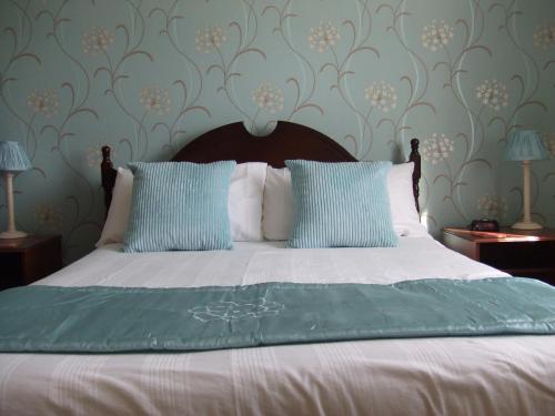 a bed with blue and white sheets and pillows at The Denewood in Sandown