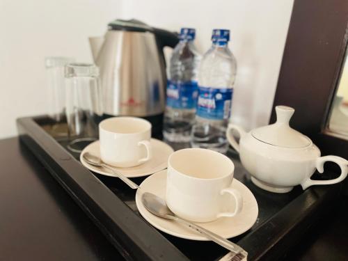 two cups and saucers on a tray with water bottles at Aradhana Airport Transit hotel in Katunayaka