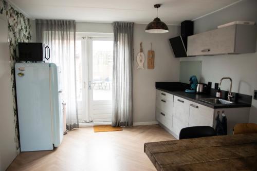een keuken met een witte koelkast en een raam bij huisje de Strandjutter in Katwijk aan Zee