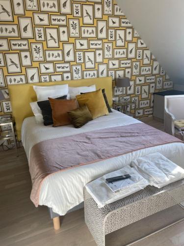 a bedroom with a large bed with a wall of pictures at L’Aubépine in Saint-Gervais-la-Forêt