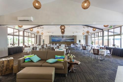 a restaurant with tables and chairs and couches at NRMA Murramarang Beachfront Holiday Resort in Durras